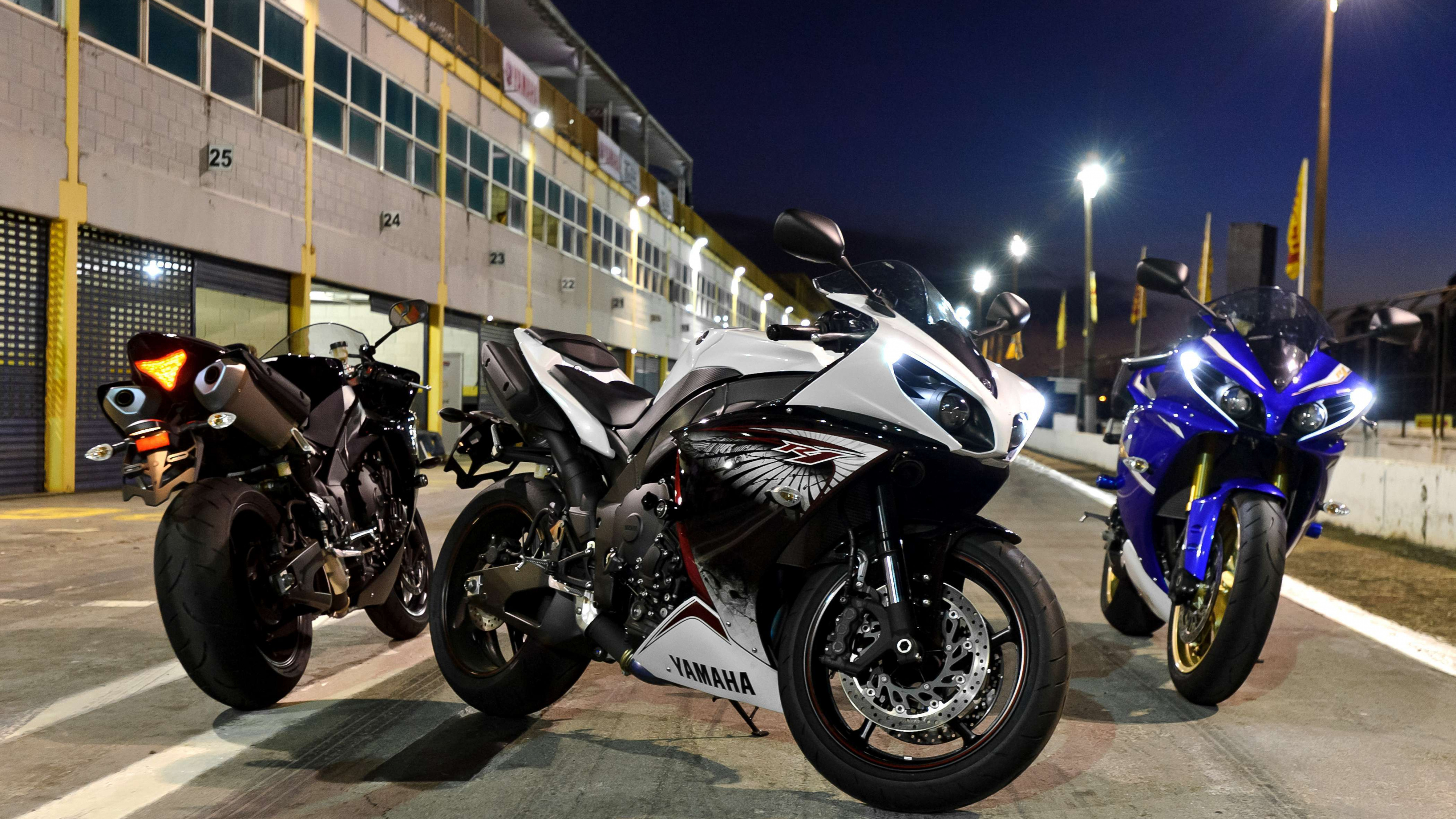 Black and White Sports Bike Parked Beside Yellow and White Bus During Night Time. Wallpaper in 3840x2160 Resolution