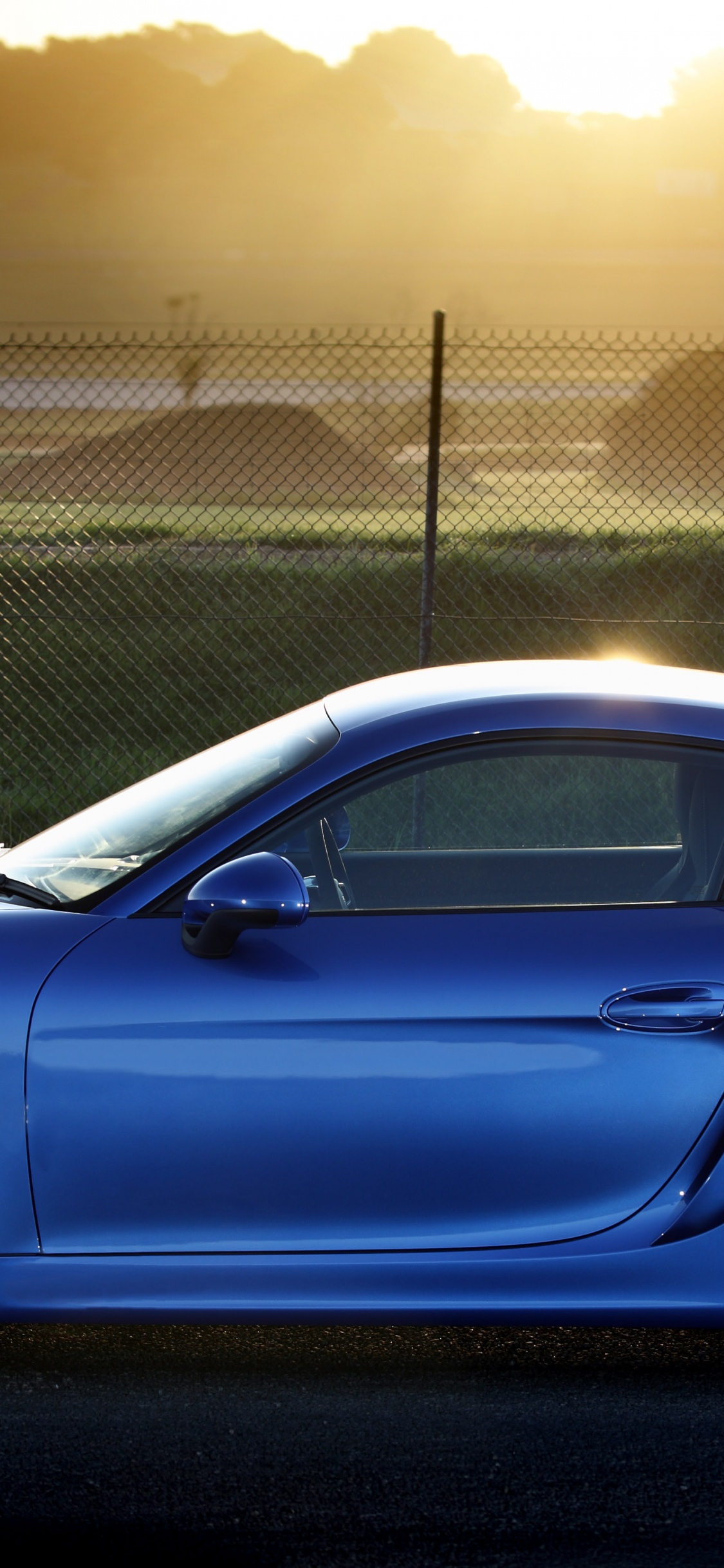 Blue Porsche 911 Parked Near Gray Metal Fence During Daytime. Wallpaper in 1125x2436 Resolution