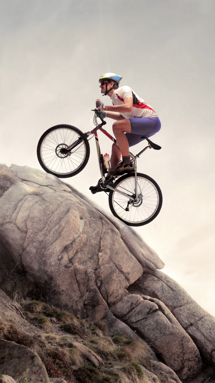 Man in Green Shirt Riding on Black Mountain Bike on Brown Rocky Mountain During Daytime. Wallpaper in 750x1334 Resolution