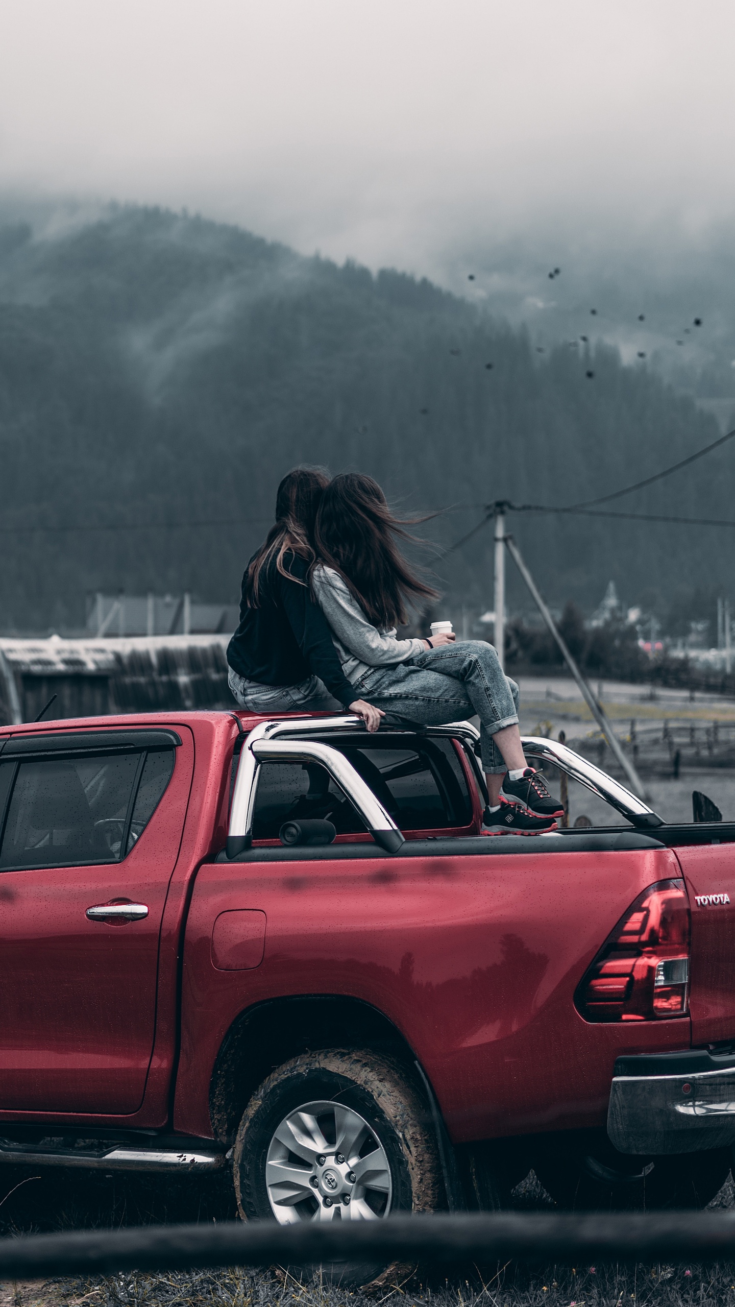Woman in Black Jacket Sitting on Red Car Hood During Daytime. Wallpaper in 1440x2560 Resolution