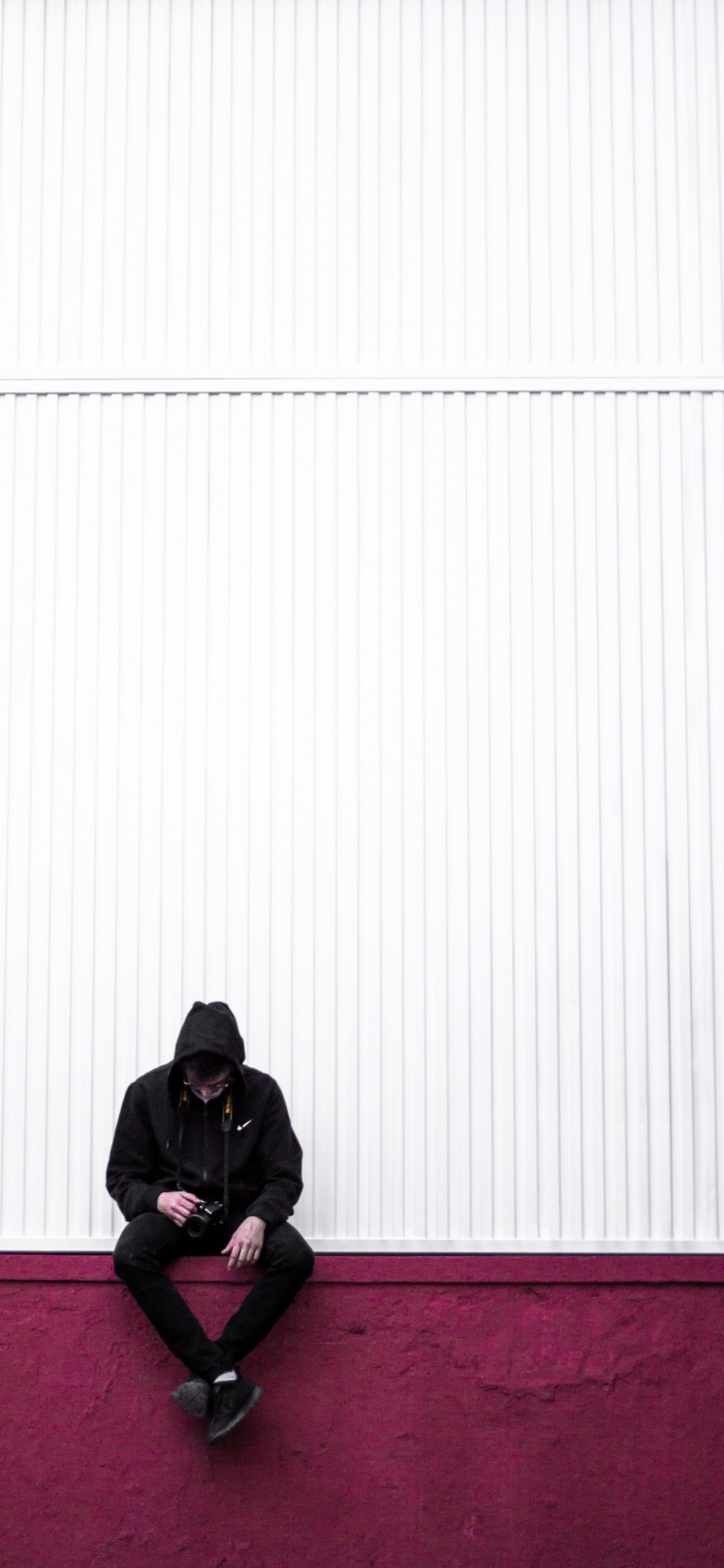 Mann in Schwarzer Jacke Sitzt Auf Rotem Teppich. Wallpaper in 1125x2436 Resolution