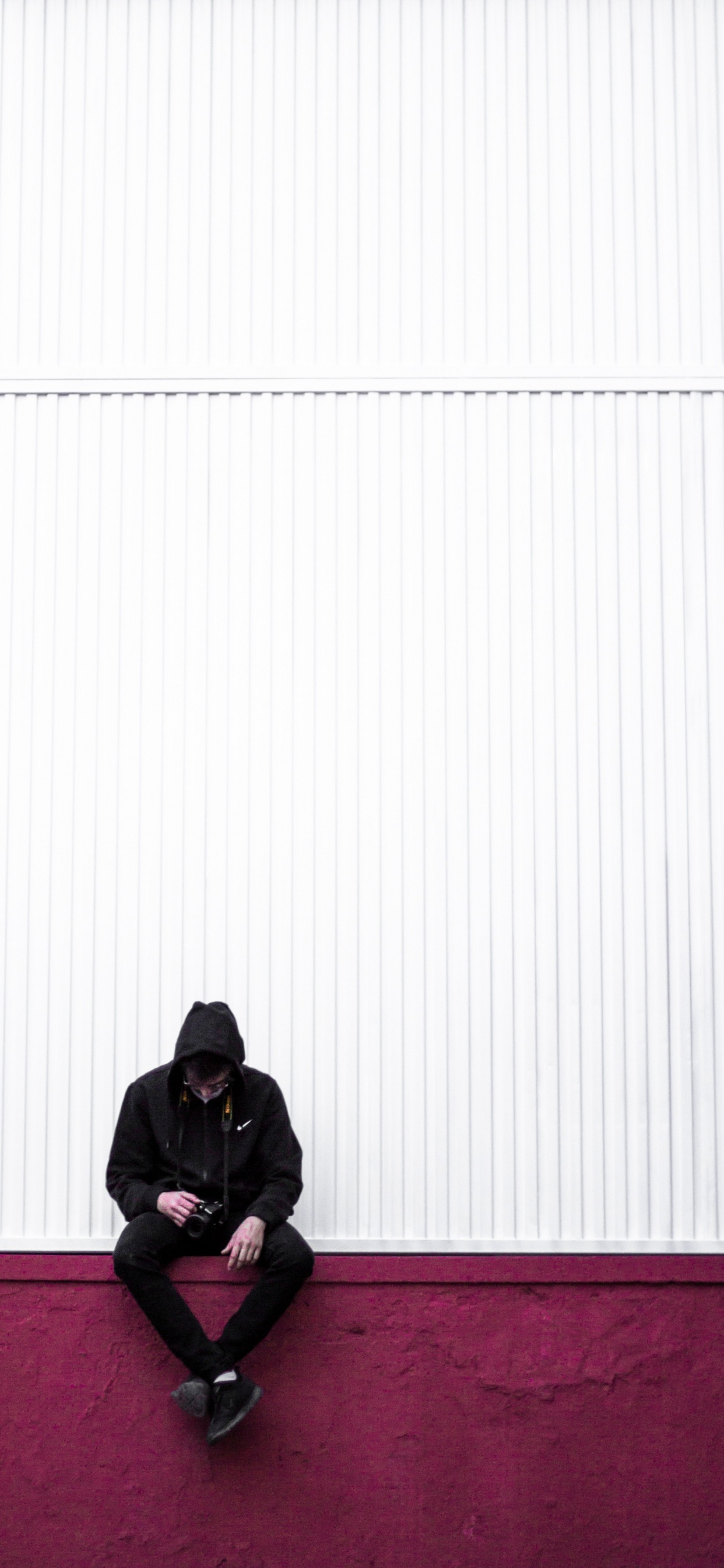 Mann in Schwarzer Jacke Sitzt Auf Rotem Teppich. Wallpaper in 1242x2688 Resolution