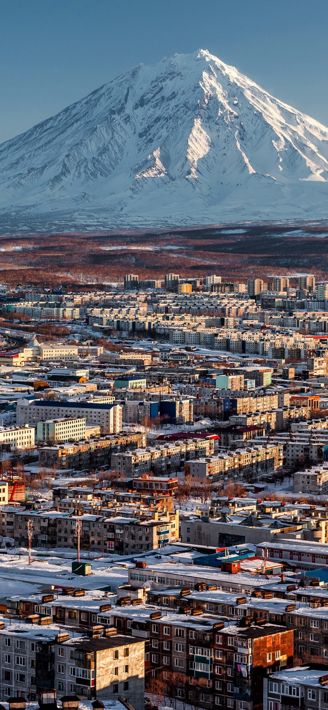 Aerial View of City Buildings Near Snow Covered Mountain During Daytime. Wallpaper in 1125x2436 Resolution