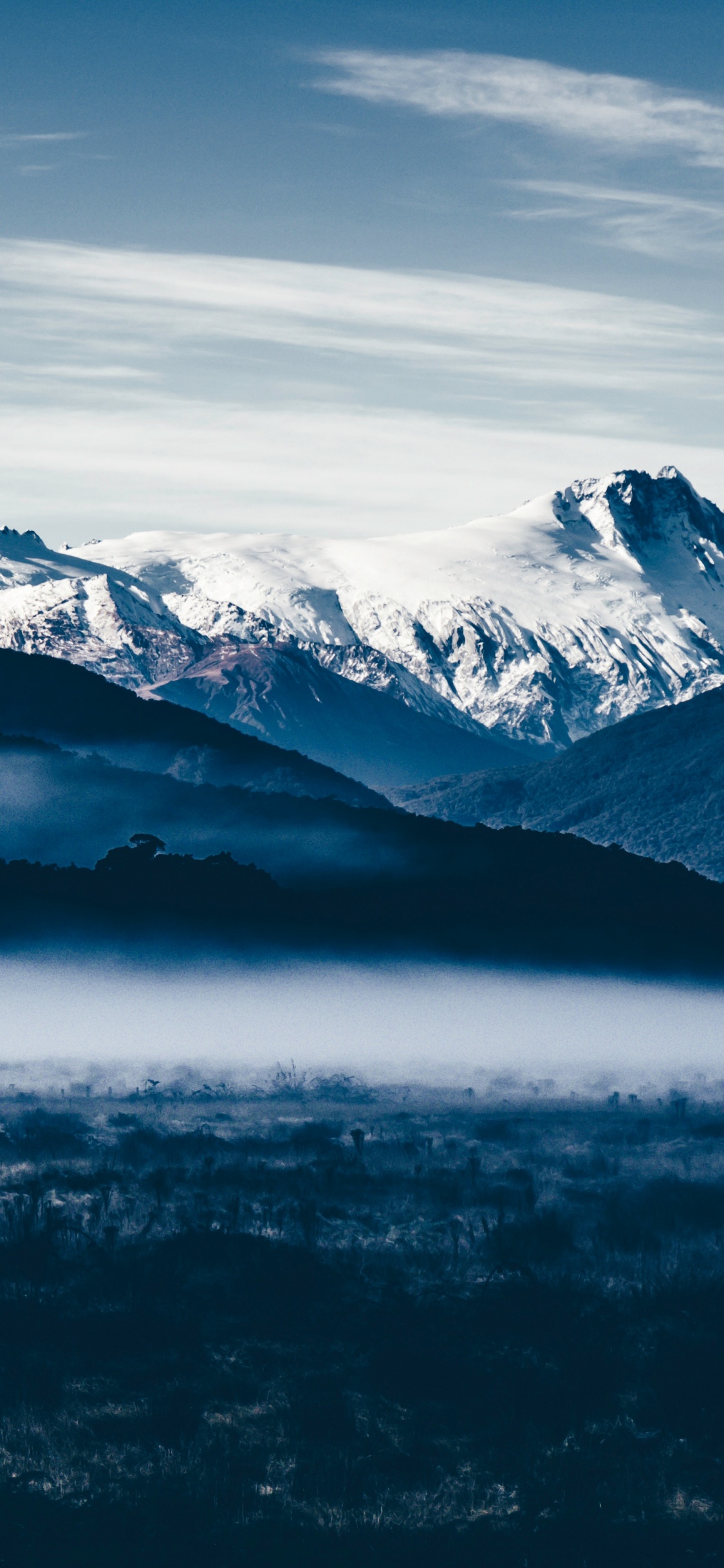 Snow Covered Mountains Under Cloudy Sky During Daytime. Wallpaper in 1125x2436 Resolution