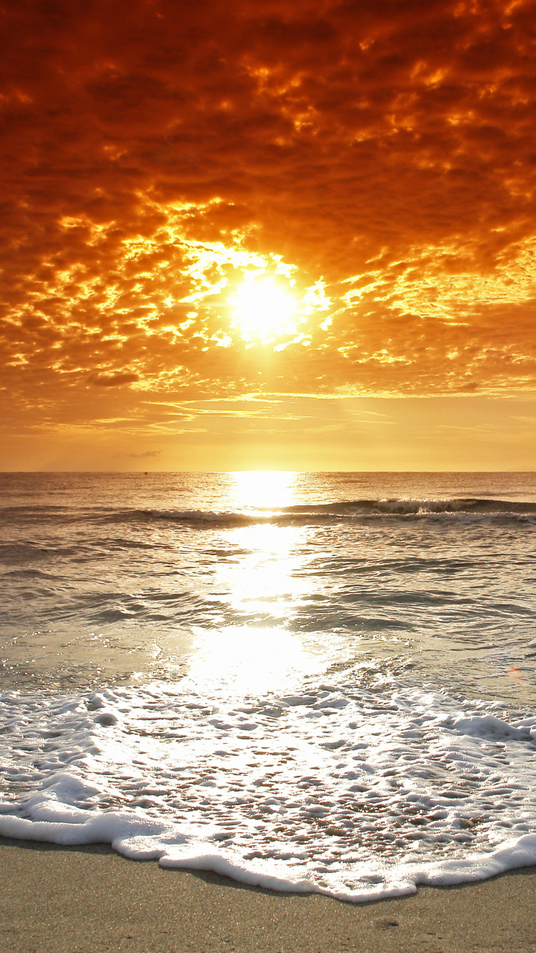 Olas Del Océano Rompiendo en la Orilla Durante la Puesta de Sol. Wallpaper in 750x1334 Resolution