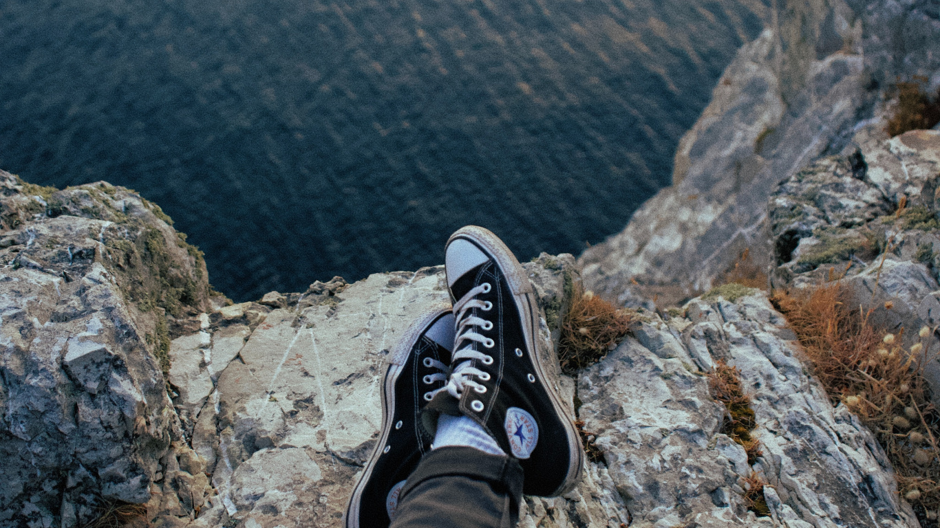 Personne en Pantalon Noir et Baskets Nike Noir et Blanc Assis Sur un Rocher. Wallpaper in 1366x768 Resolution