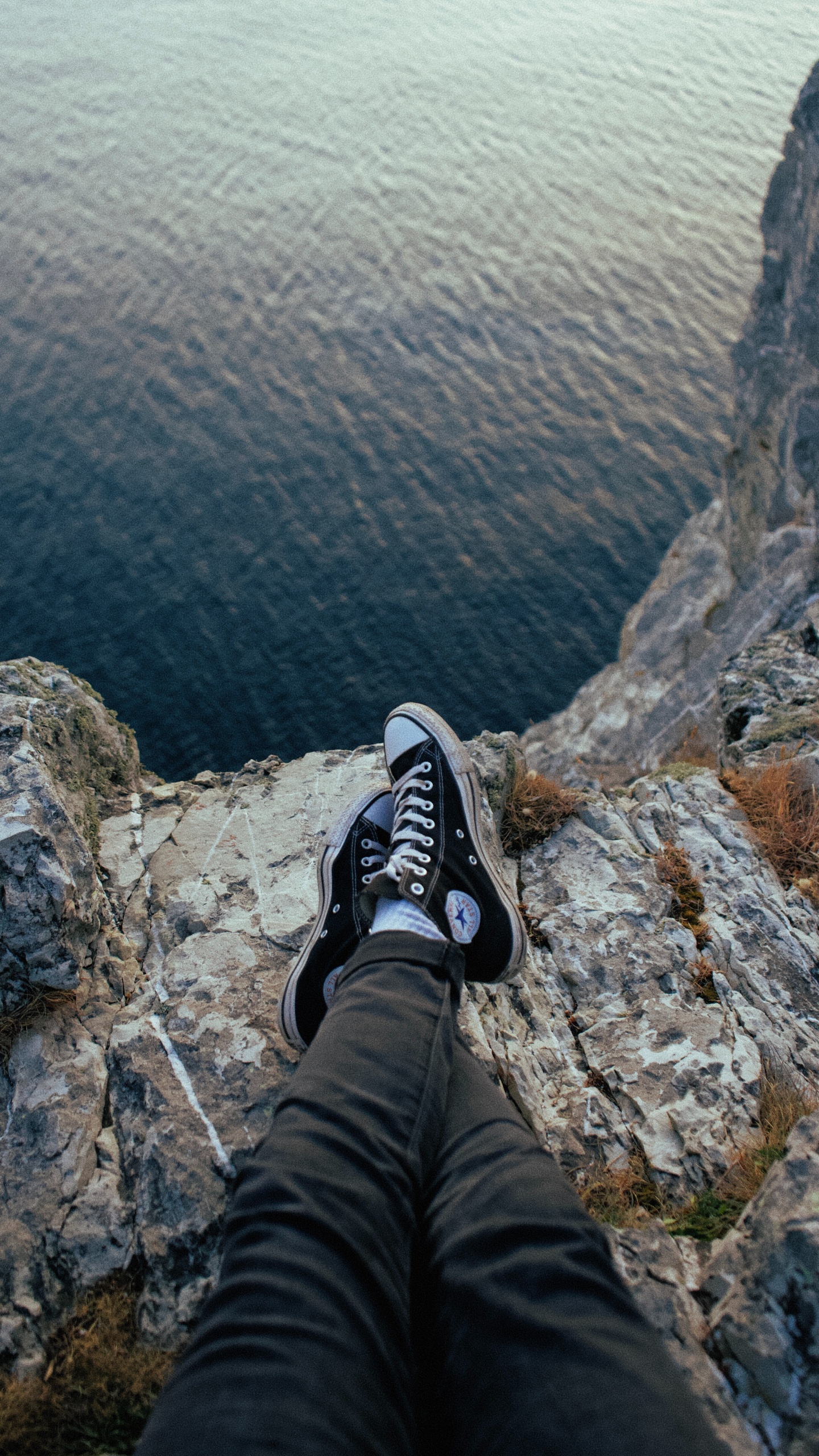 Person in Schwarzen Hosen Und Schwarz-weißen Nike-Turnschuhen, Die Auf Felsen Sitzen Sitting. Wallpaper in 1440x2560 Resolution