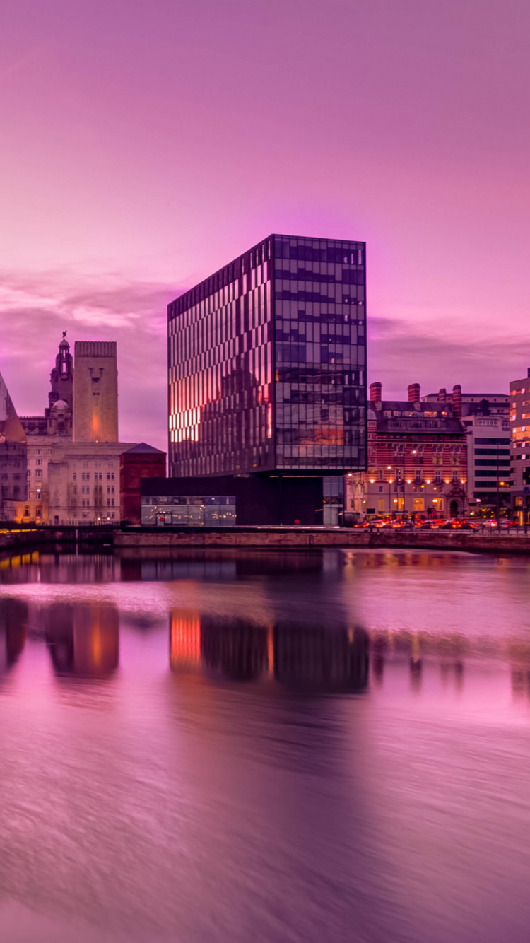 Skyline Der Stadt in Der Nähe Von Gewässern Bei Sonnenuntergang. Wallpaper in 750x1334 Resolution