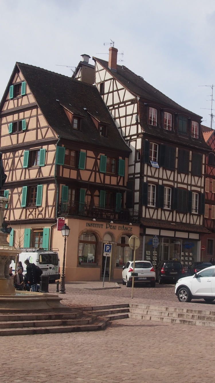Cars Parked Beside Brown Concrete Building During Daytime. Wallpaper in 750x1334 Resolution