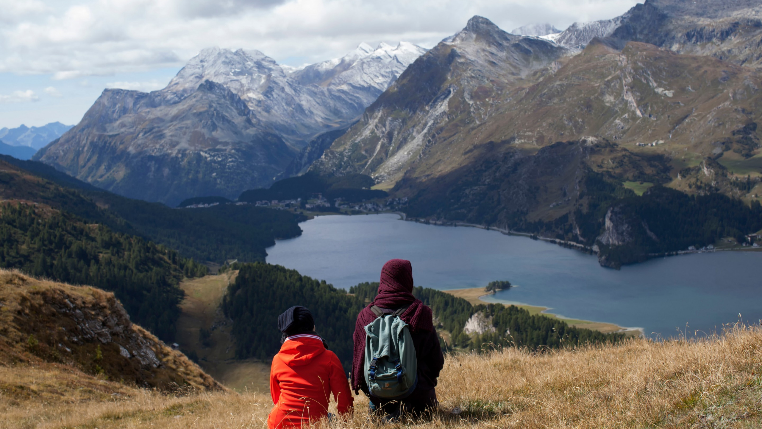 Personne en Sweat à Capuche Rouge et Noir Assis Sur un Terrain D'herbe Verte Près du Lac et Des Montagnes Pendant. Wallpaper in 2560x1440 Resolution