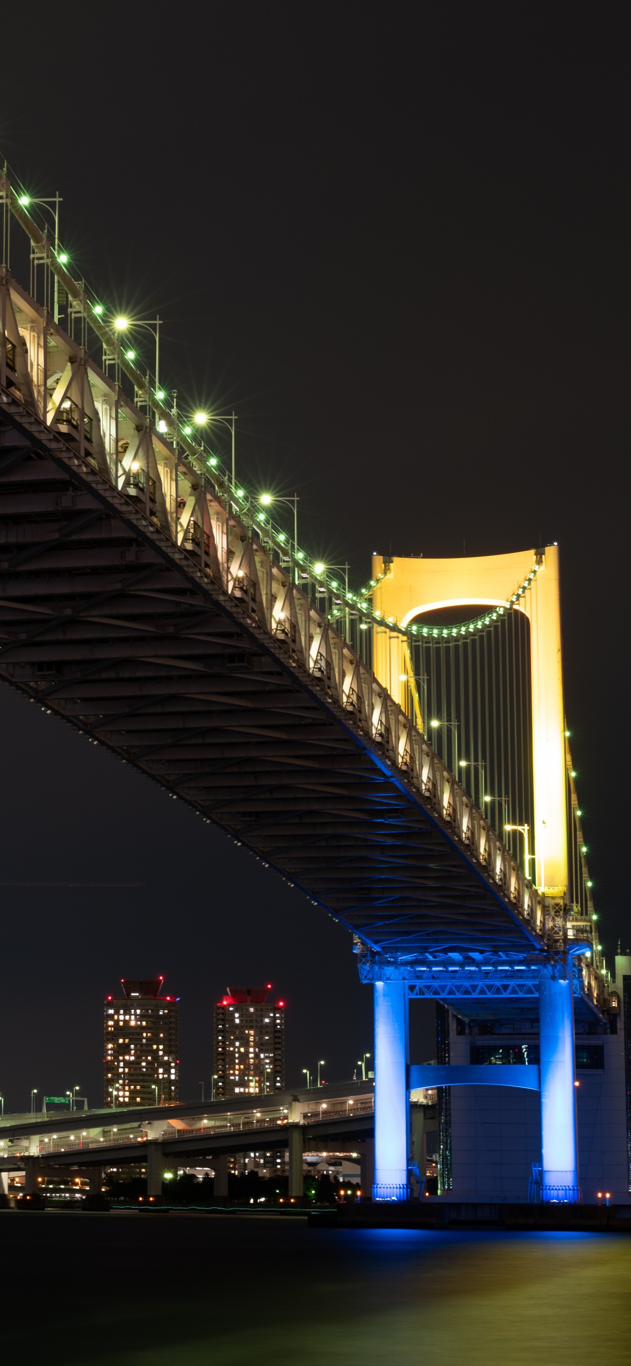 Blau Beleuchtete Brücke Während Der Nacht. Wallpaper in 1242x2688 Resolution