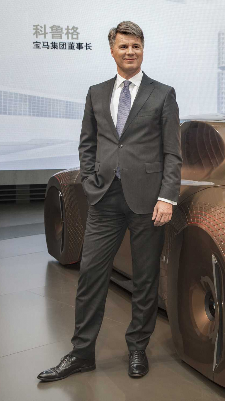 Mann im Schwarzen Anzug, Der Neben Rotem Auto Steht. Wallpaper in 750x1334 Resolution