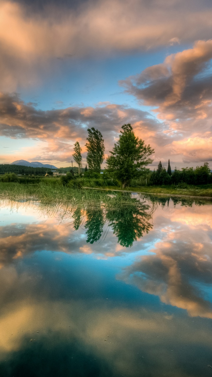 Green Grass Field Near Body of Water Under Cloudy Sky During Daytime. Wallpaper in 720x1280 Resolution