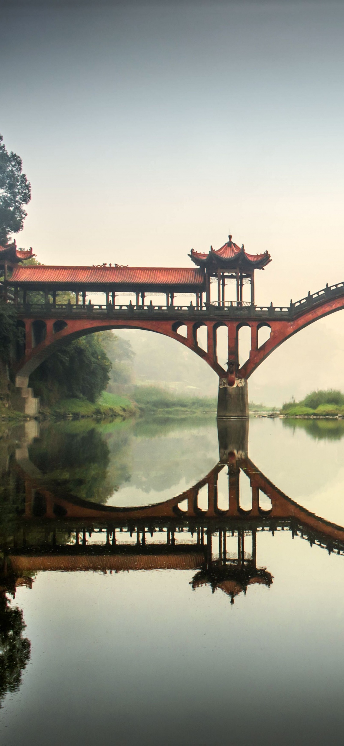 Brown Bridge Over Body of Water. Wallpaper in 1125x2436 Resolution