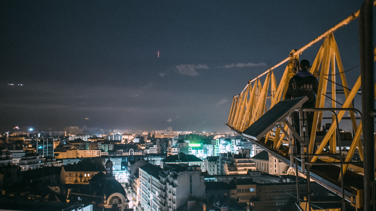 Yellow Metal Crane Near City Buildings During Night Time. Wallpaper in 1280x720 Resolution
