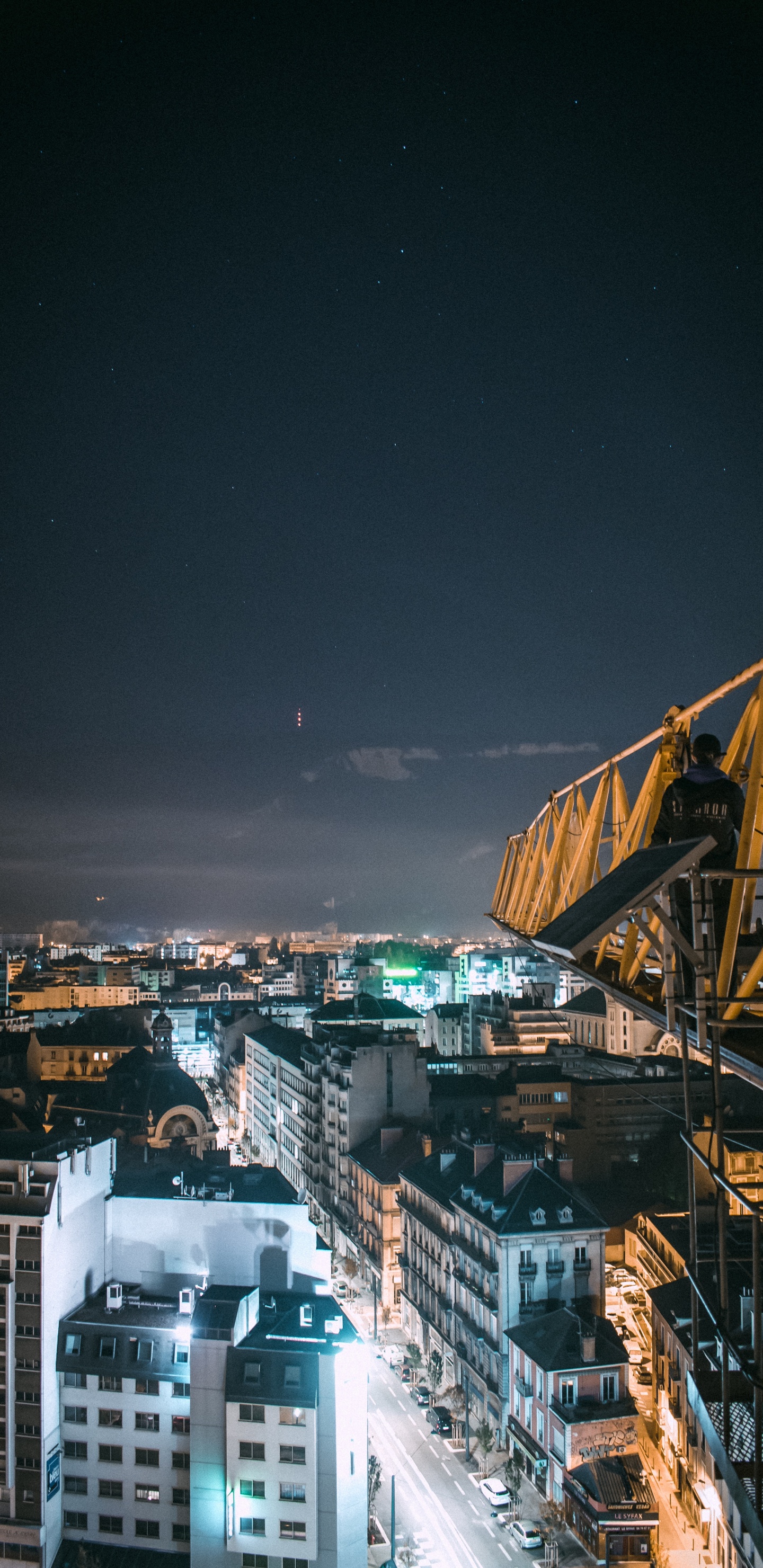 Yellow Metal Crane Near City Buildings During Night Time. Wallpaper in 1440x2960 Resolution