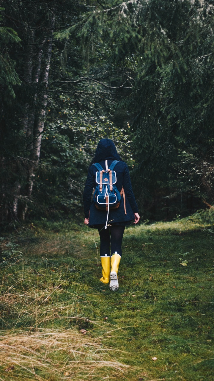 Frau in Schwarz-roter Jacke Steht Auf Grüner Wiese. Wallpaper in 720x1280 Resolution