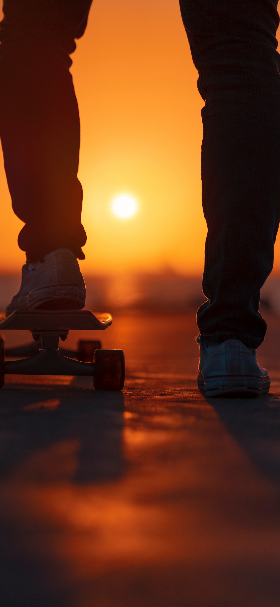 Person in Black Pants and White Sneakers Standing on Brown Wooden Skateboard. Wallpaper in 1125x2436 Resolution