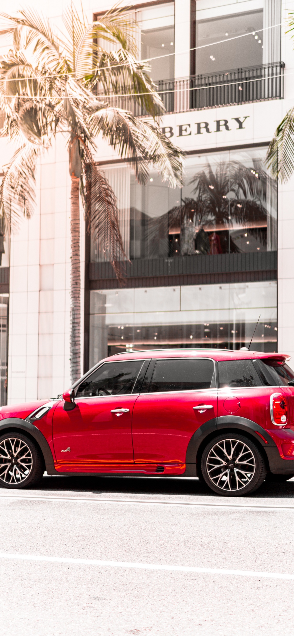 Sedán Rojo Estacionado Cerca Del Edificio Durante el Día. Wallpaper in 1125x2436 Resolution