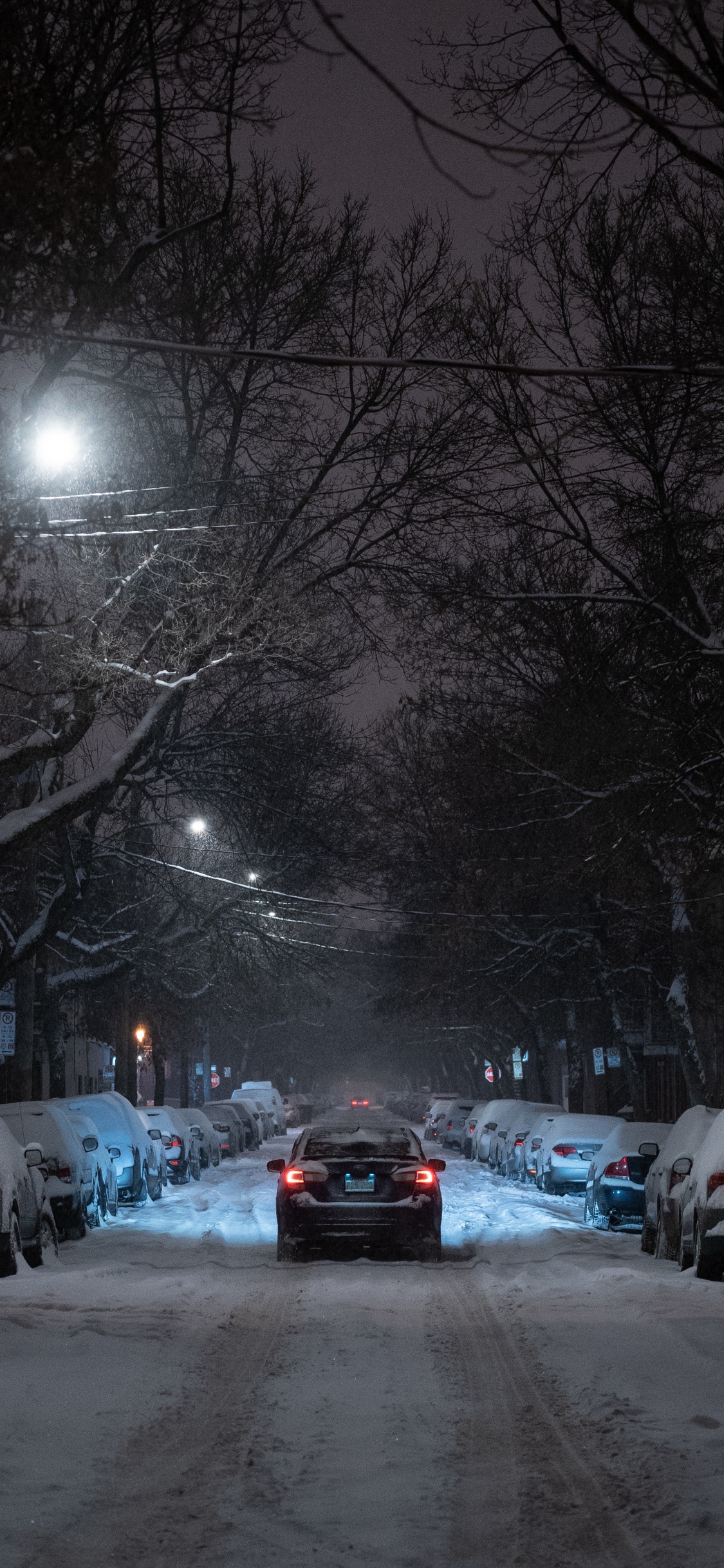 Cars Parked on Snow Covered Road During Night Time. Wallpaper in 1125x2436 Resolution