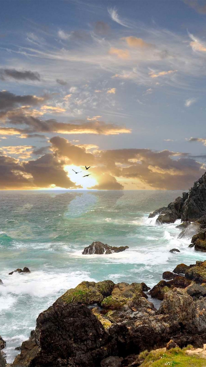 Brauner Felsiger Berg am Meer Bei Sonnenuntergang. Wallpaper in 720x1280 Resolution