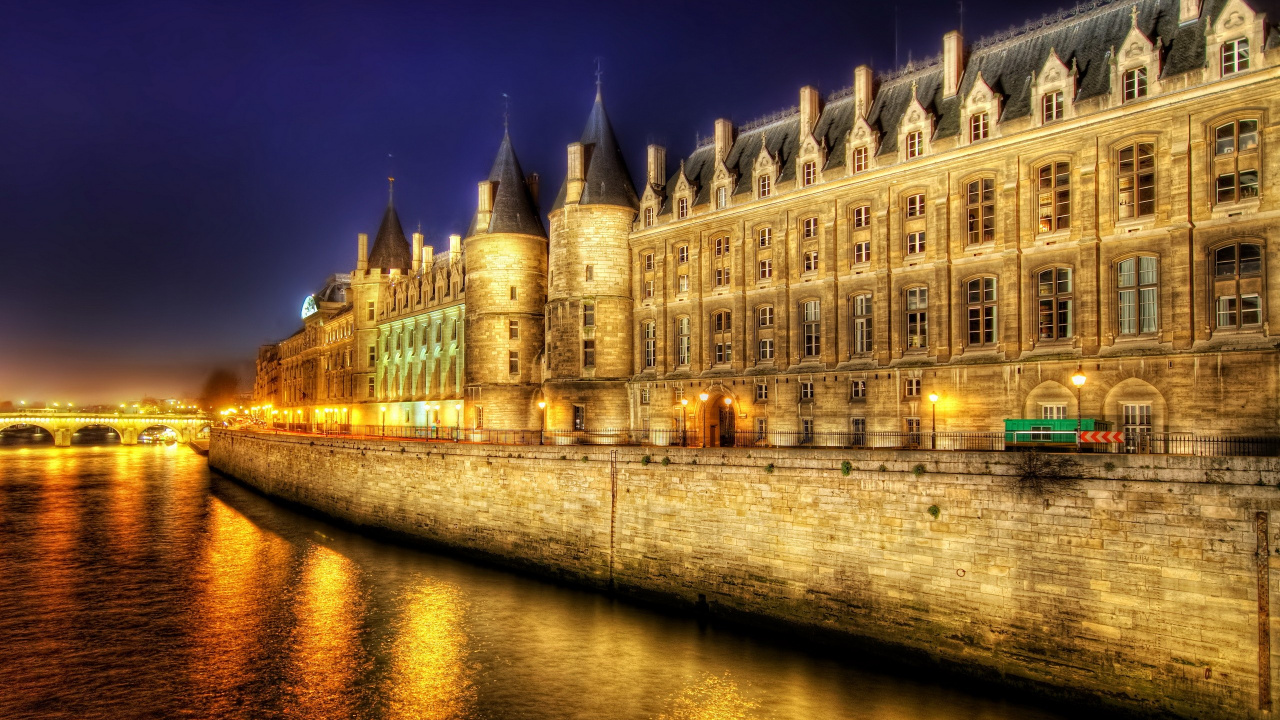 Brown Concrete Building Near Body of Water During Night Time. Wallpaper in 1280x720 Resolution