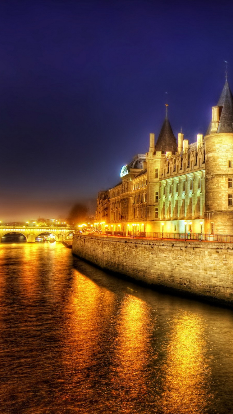 Brown Concrete Building Near Body of Water During Night Time. Wallpaper in 750x1334 Resolution