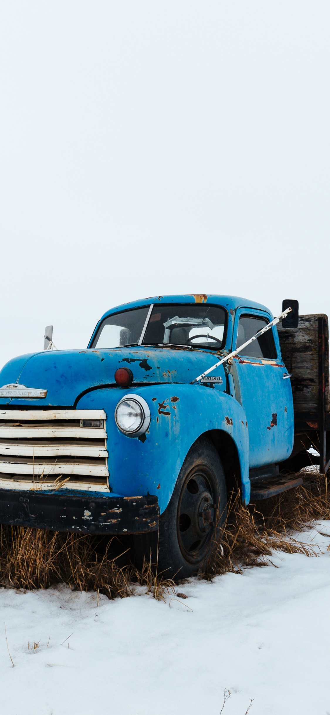 Camión Azul Sobre Suelo Cubierto de Nieve Durante el Día. Wallpaper in 1125x2436 Resolution