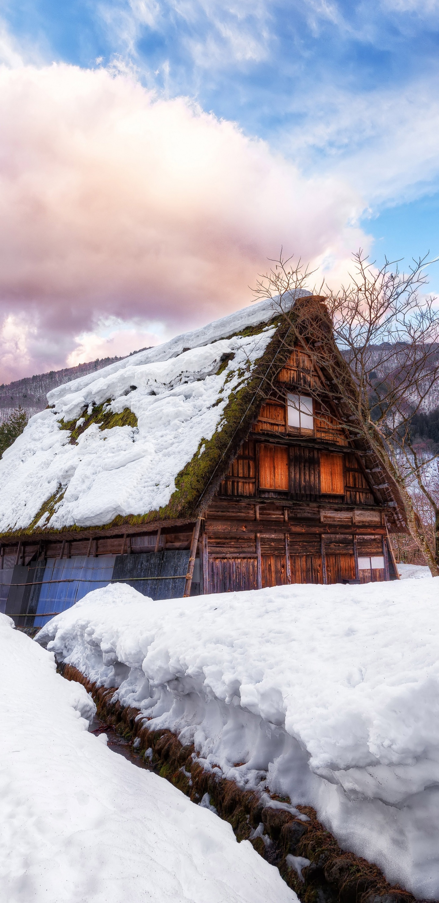 Casa de Madera Marrón Sobre Suelo Cubierto de Nieve Bajo Las Nubes Blancas y el Cielo Azul Durante el Día. Wallpaper in 1440x2960 Resolution