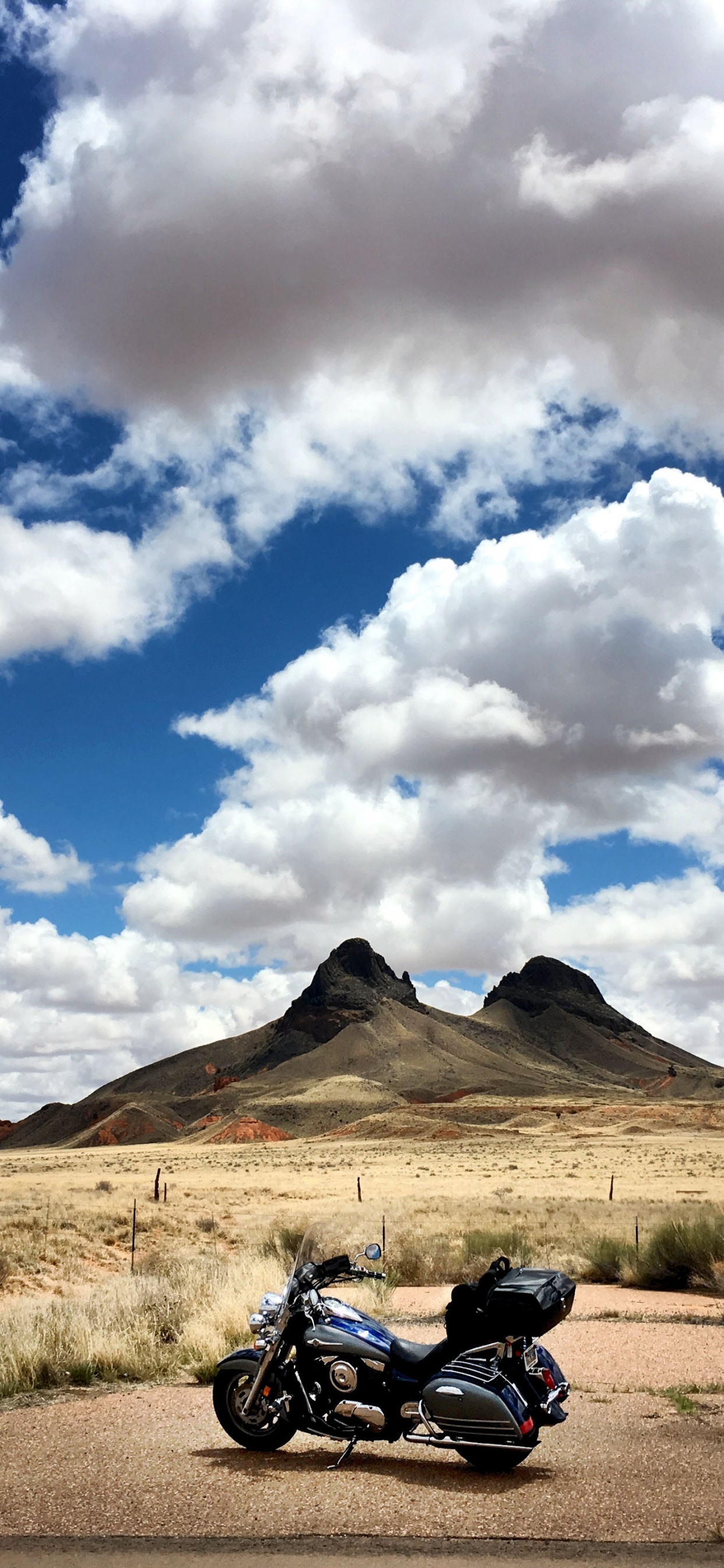 Motocicleta Negra en Campo Marrón Bajo Nubes Blancas y Cielo Azul Durante el Día. Wallpaper in 1242x2688 Resolution