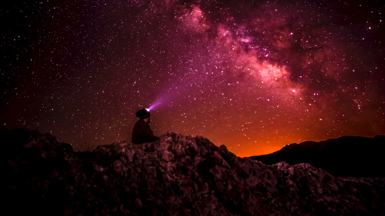 Man Sitting on Rock Under Starry Night. Wallpaper in 1280x720 Resolution