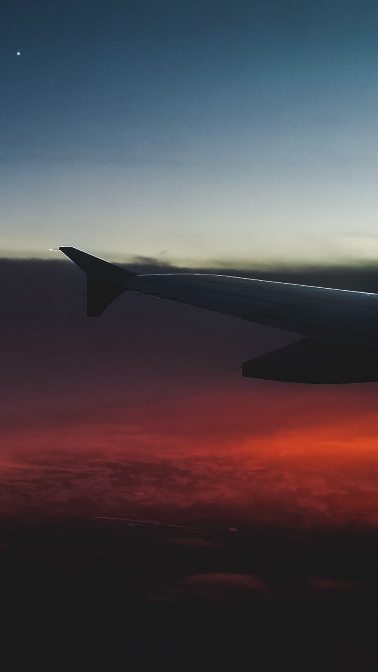 Flugzeugflügel Über Den Wolken Bei Sonnenuntergang. Wallpaper in 750x1334 Resolution