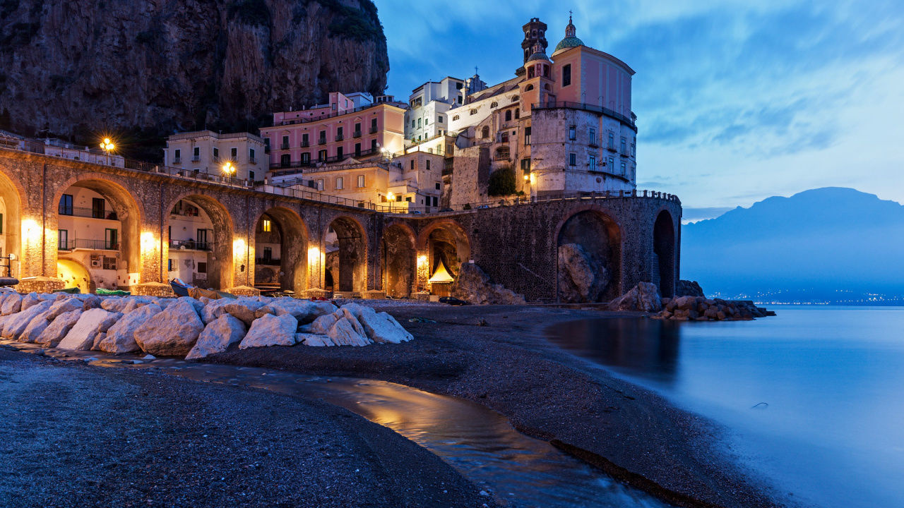 Edificio de Hormigón Marrón Cerca Del Cuerpo de Agua Durante la Noche. Wallpaper in 1280x720 Resolution