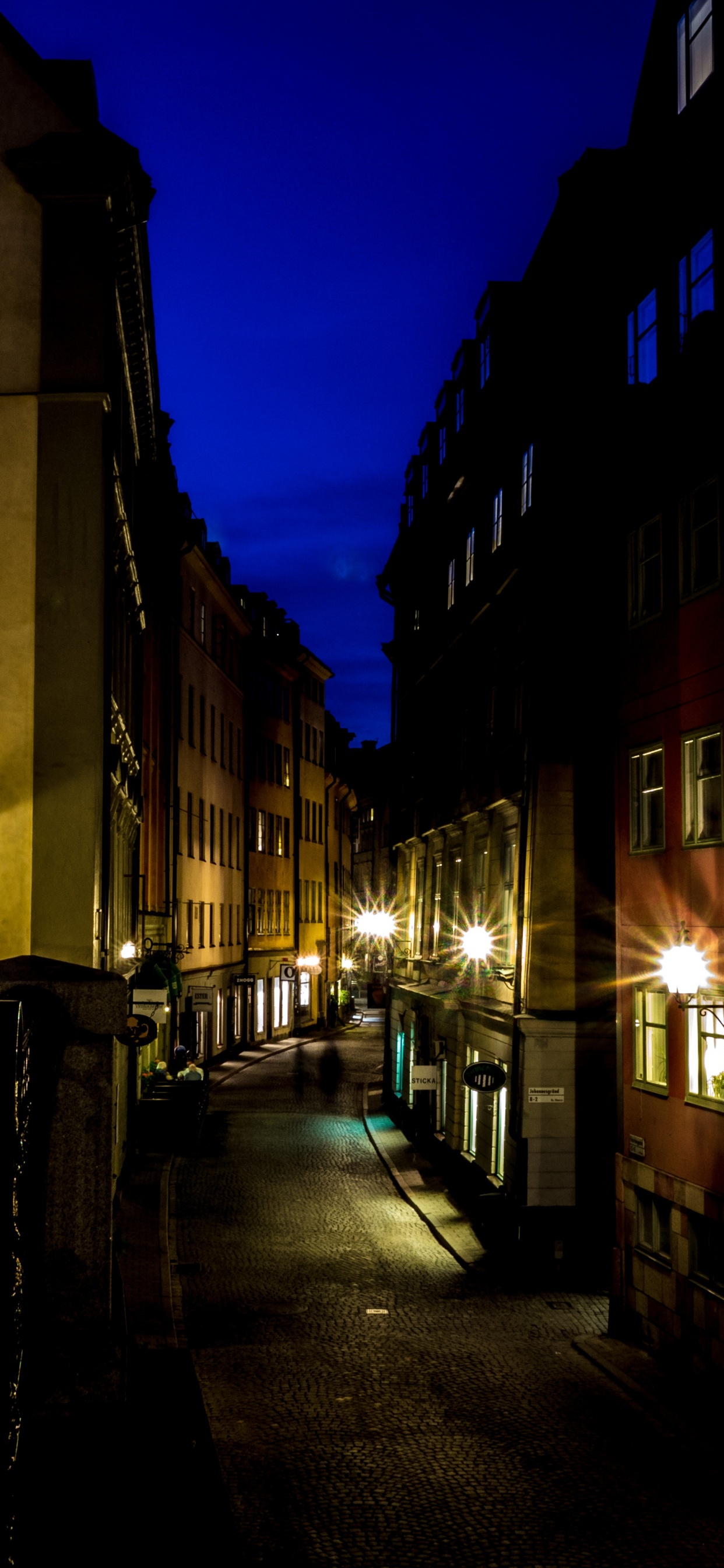 Personnes Marchant Sur le Trottoir Près du Bâtiment Pendant la Nuit. Wallpaper in 1242x2688 Resolution