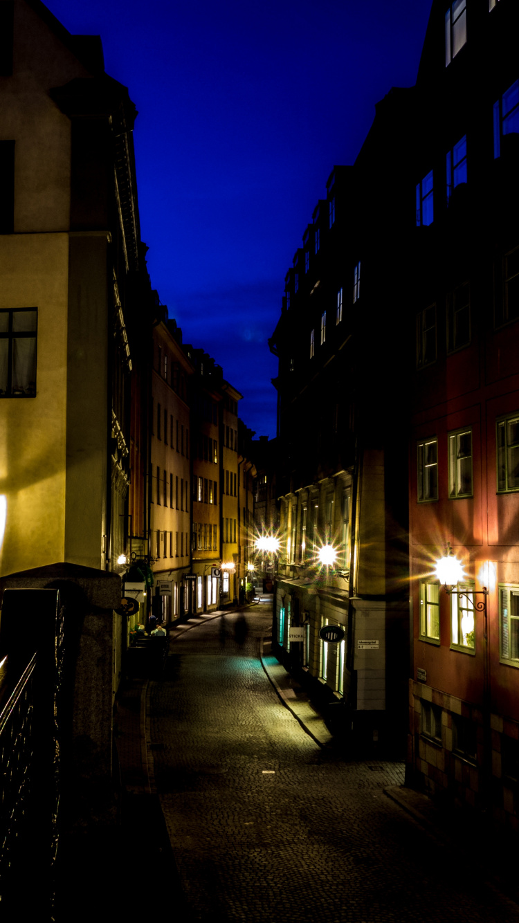 Personnes Marchant Sur le Trottoir Près du Bâtiment Pendant la Nuit. Wallpaper in 750x1334 Resolution