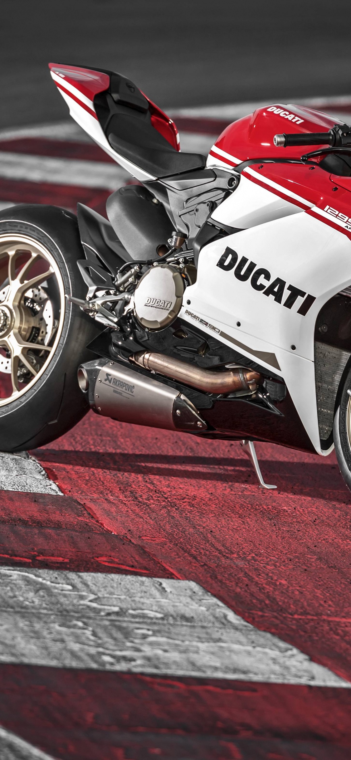 Vélo de Sport Rouge et Blanc Sur Piste. Wallpaper in 1125x2436 Resolution