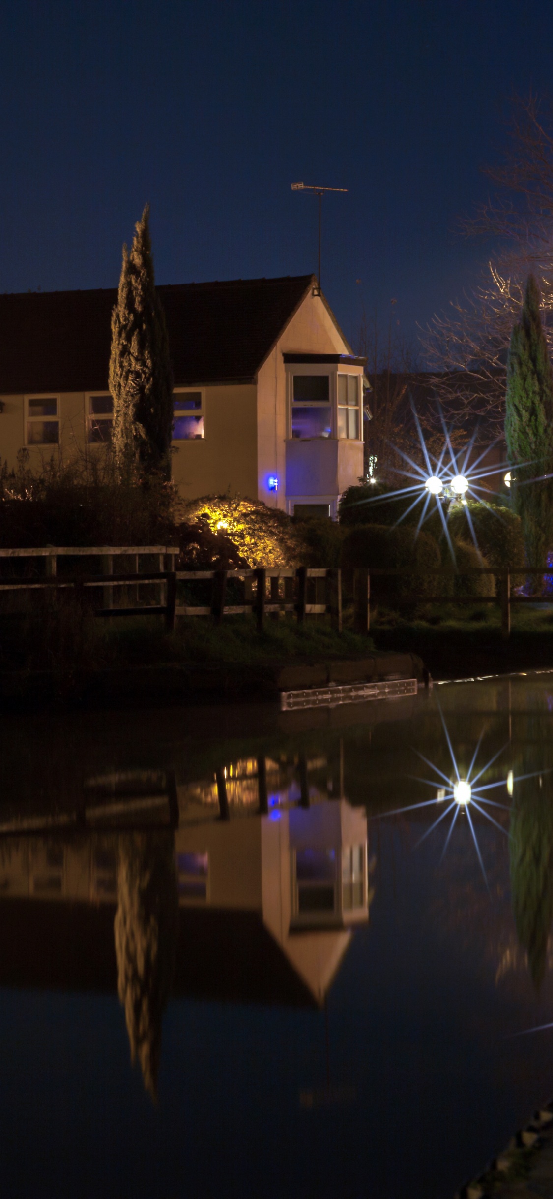 Brown and White Concrete House Near Body of Water During Night Time. Wallpaper in 1125x2436 Resolution