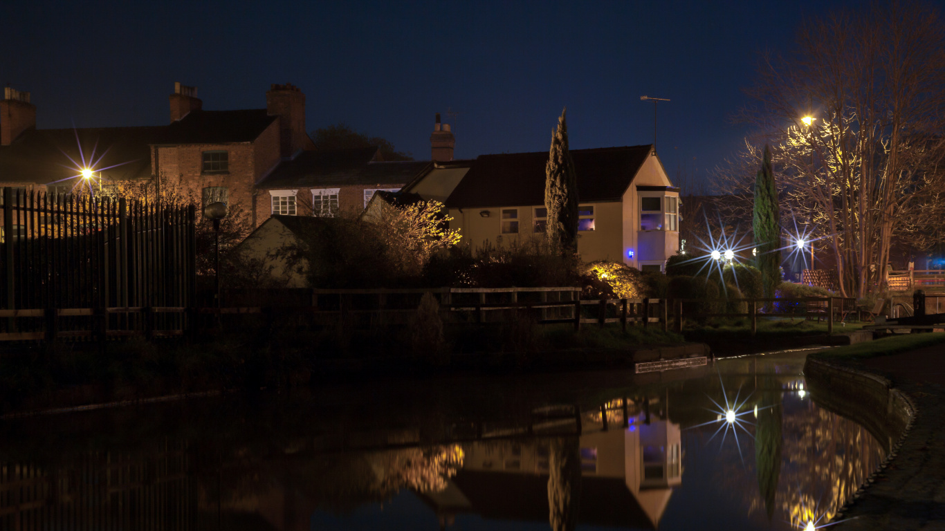 Brown and White Concrete House Near Body of Water During Night Time. Wallpaper in 1366x768 Resolution