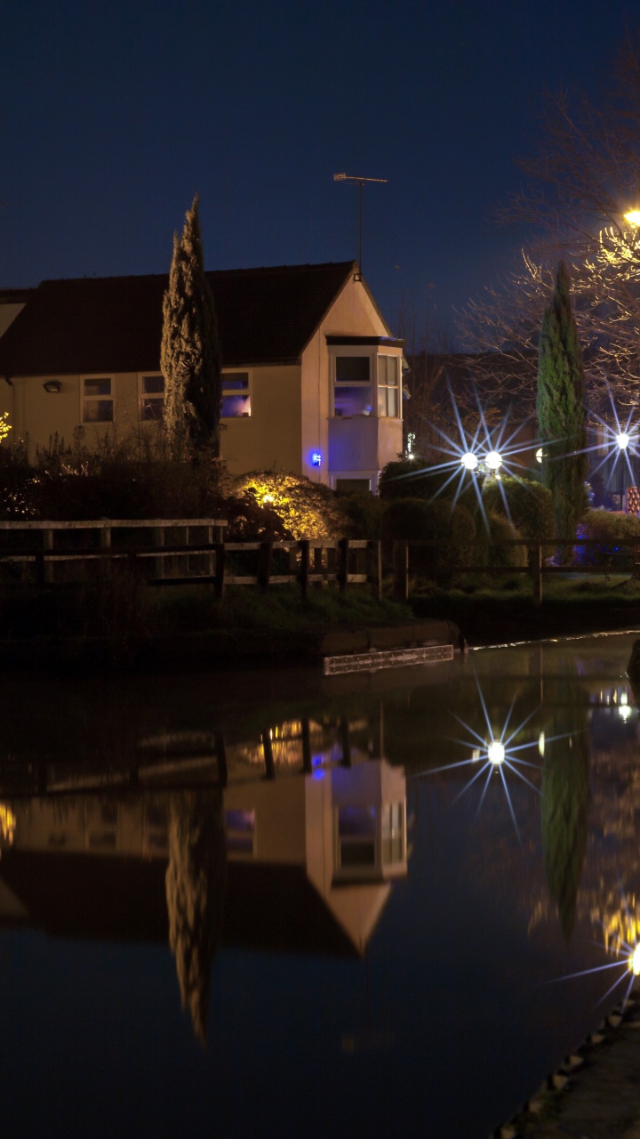 Brown and White Concrete House Near Body of Water During Night Time. Wallpaper in 720x1280 Resolution