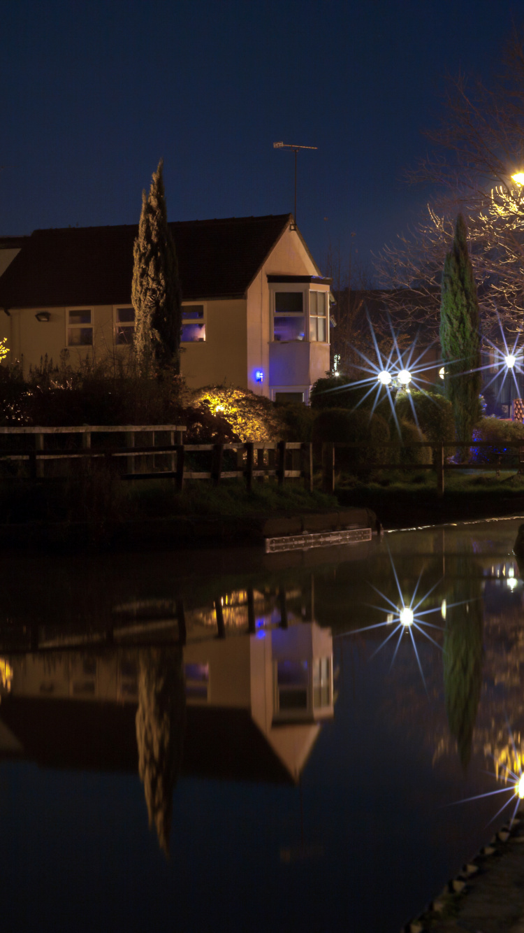 Brown and White Concrete House Near Body of Water During Night Time. Wallpaper in 750x1334 Resolution