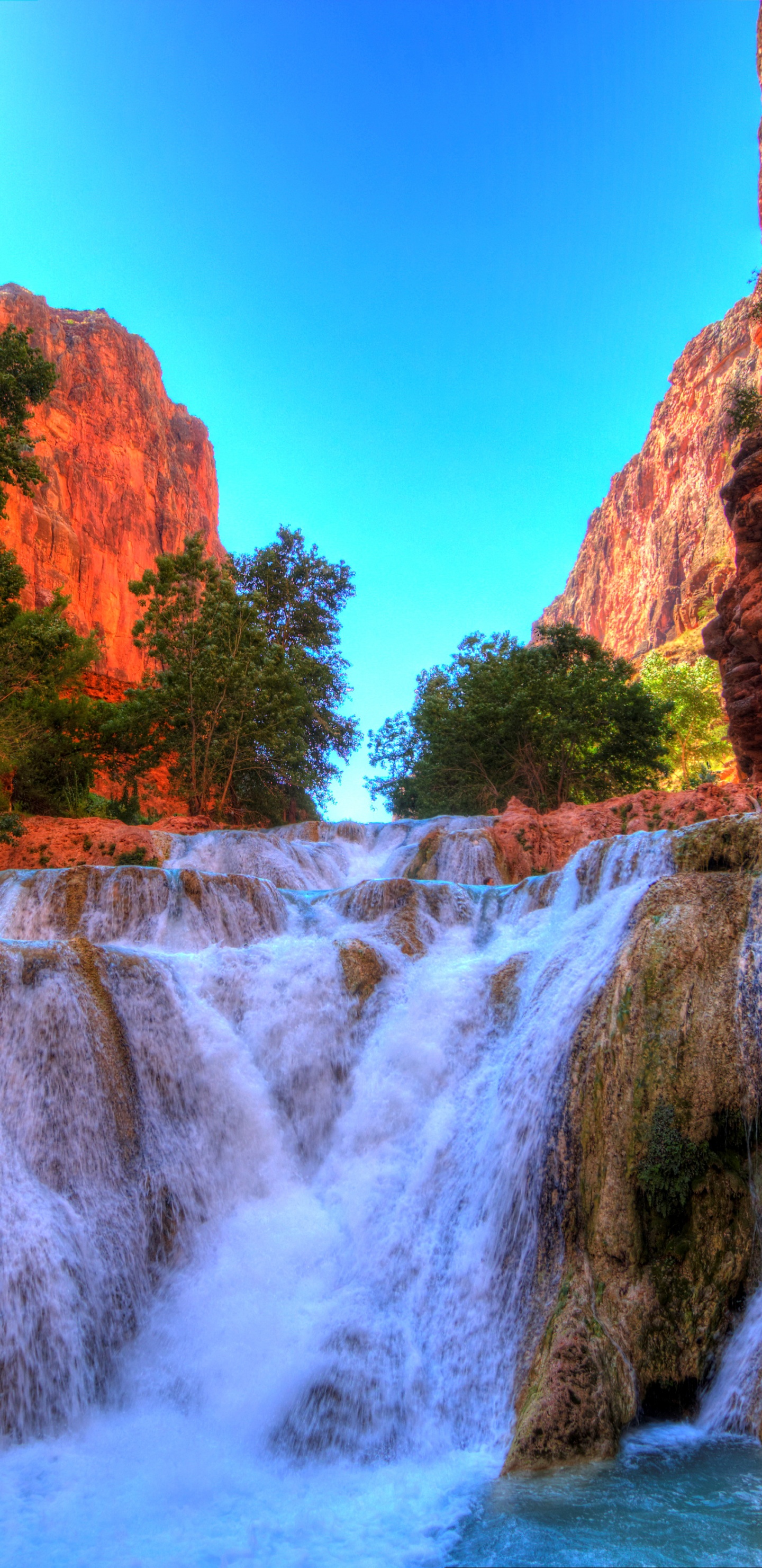 Waterfalls Between Brown Rocky Mountain Under Blue Sky During Daytime. Wallpaper in 1440x2960 Resolution