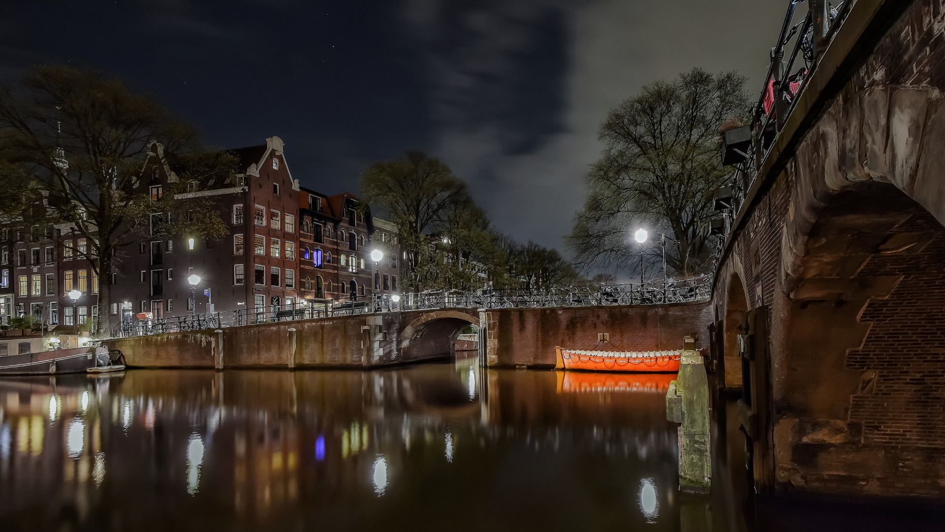 Brown Concrete Building Near River Under Gray Sky. Wallpaper in 1920x1080 Resolution