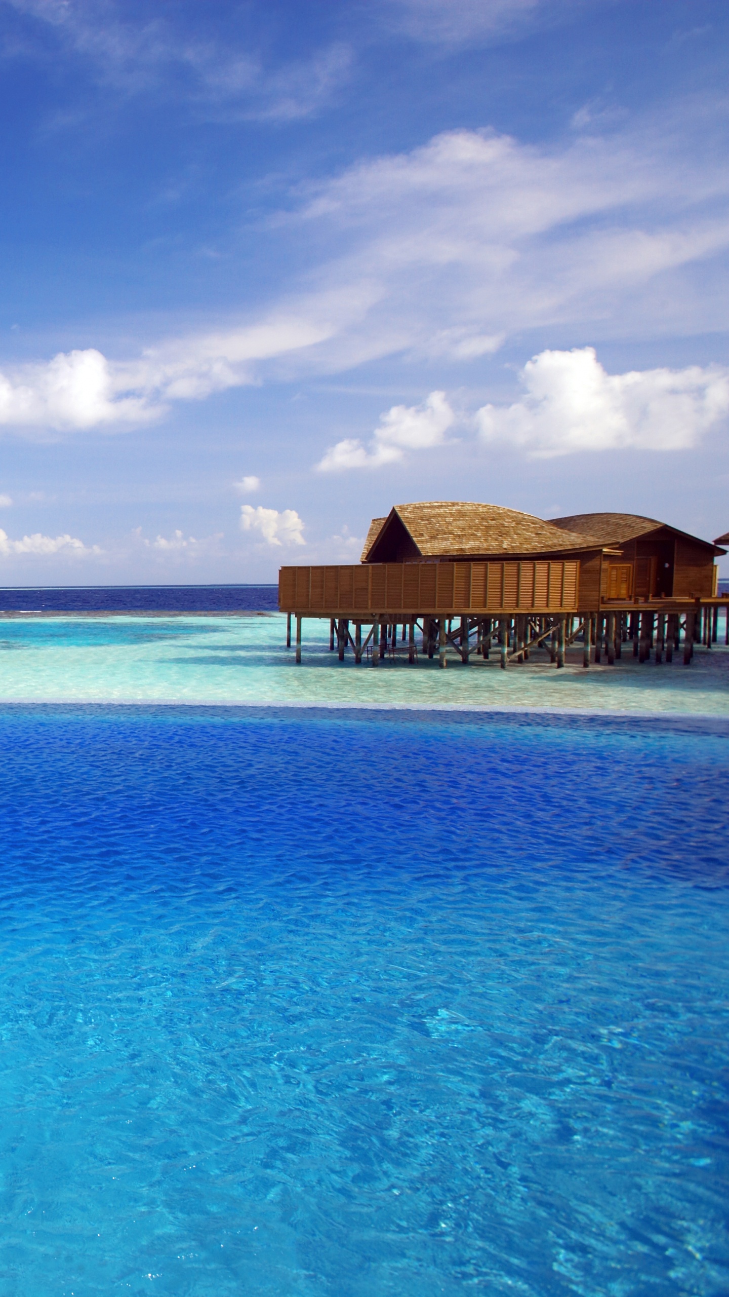 Brown Wooden House on Blue Sea Under Blue Sky and White Clouds During Daytime. Wallpaper in 1440x2560 Resolution