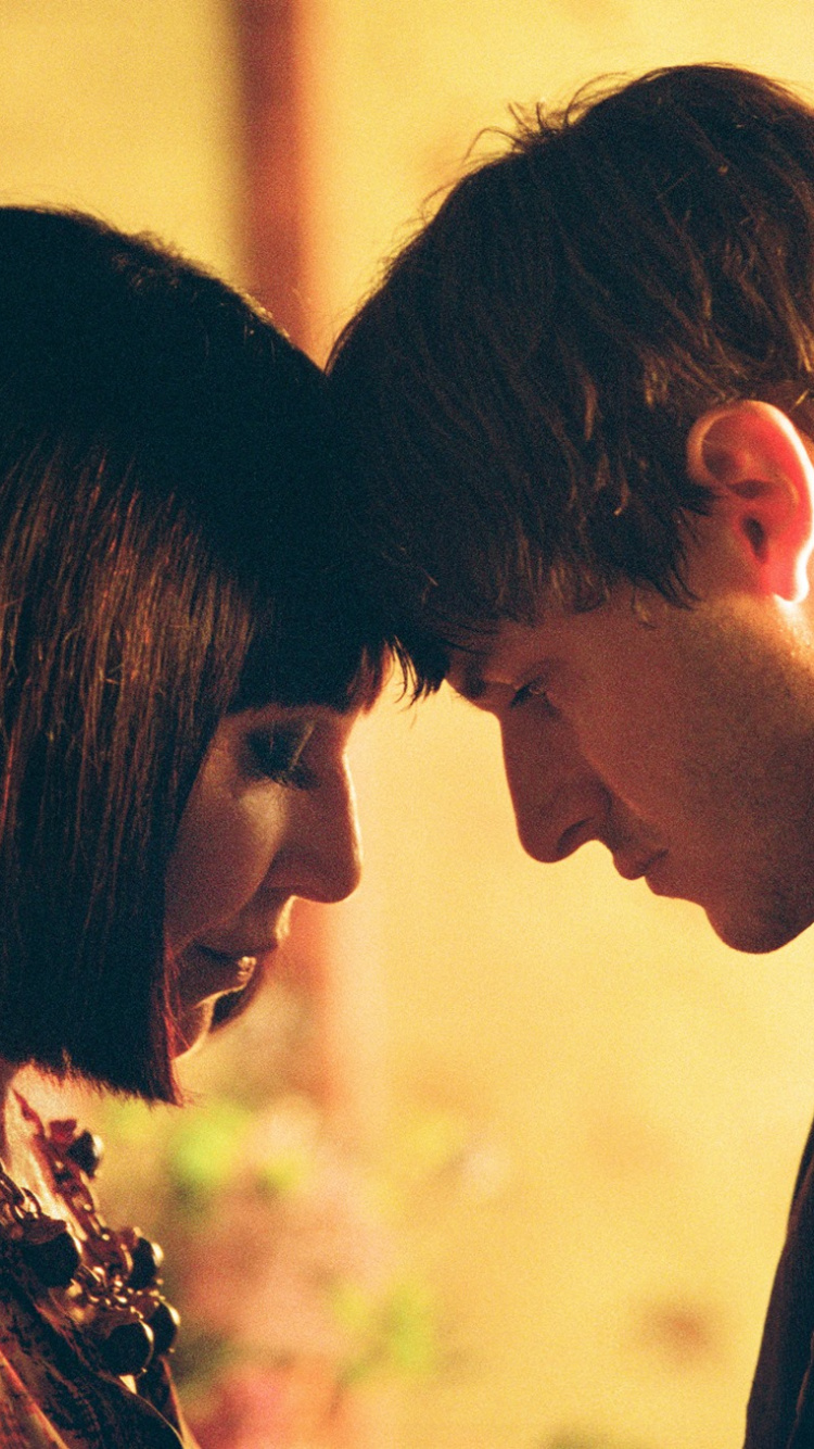 Hombre Con Chaqueta de Traje Negro Besando a Una Mujer Con Camisa Floral Marrón. Wallpaper in 750x1334 Resolution