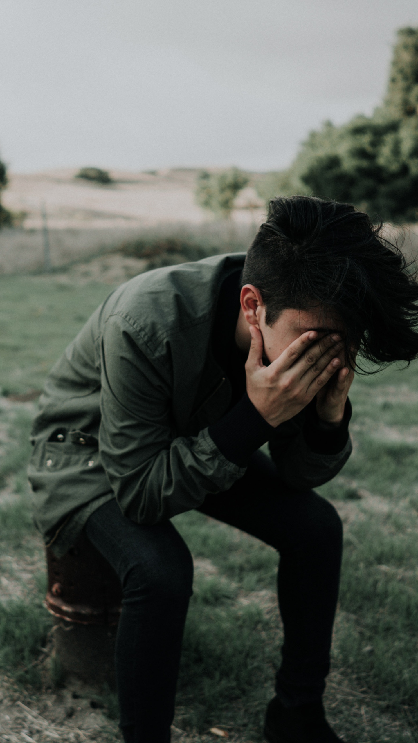 Man in Gray Jacket and Black Pants Sitting on Gray Sand During Daytime. Wallpaper in 1440x2560 Resolution