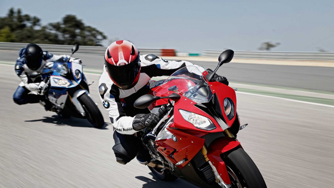 Mann im Roten Und Schwarzen Motorradanzug, Der Auf Einem Roten Und Weißen Sportmotorrad Fährt. Wallpaper in 1280x720 Resolution