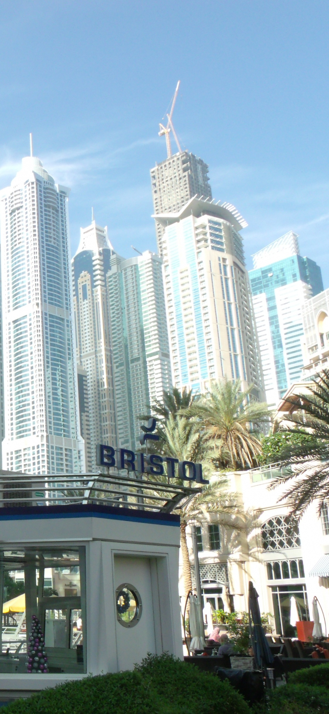 Menschen, Die Tagsüber in Der Nähe Von Hochhäusern Auf Der Straße Gehen. Wallpaper in 1125x2436 Resolution