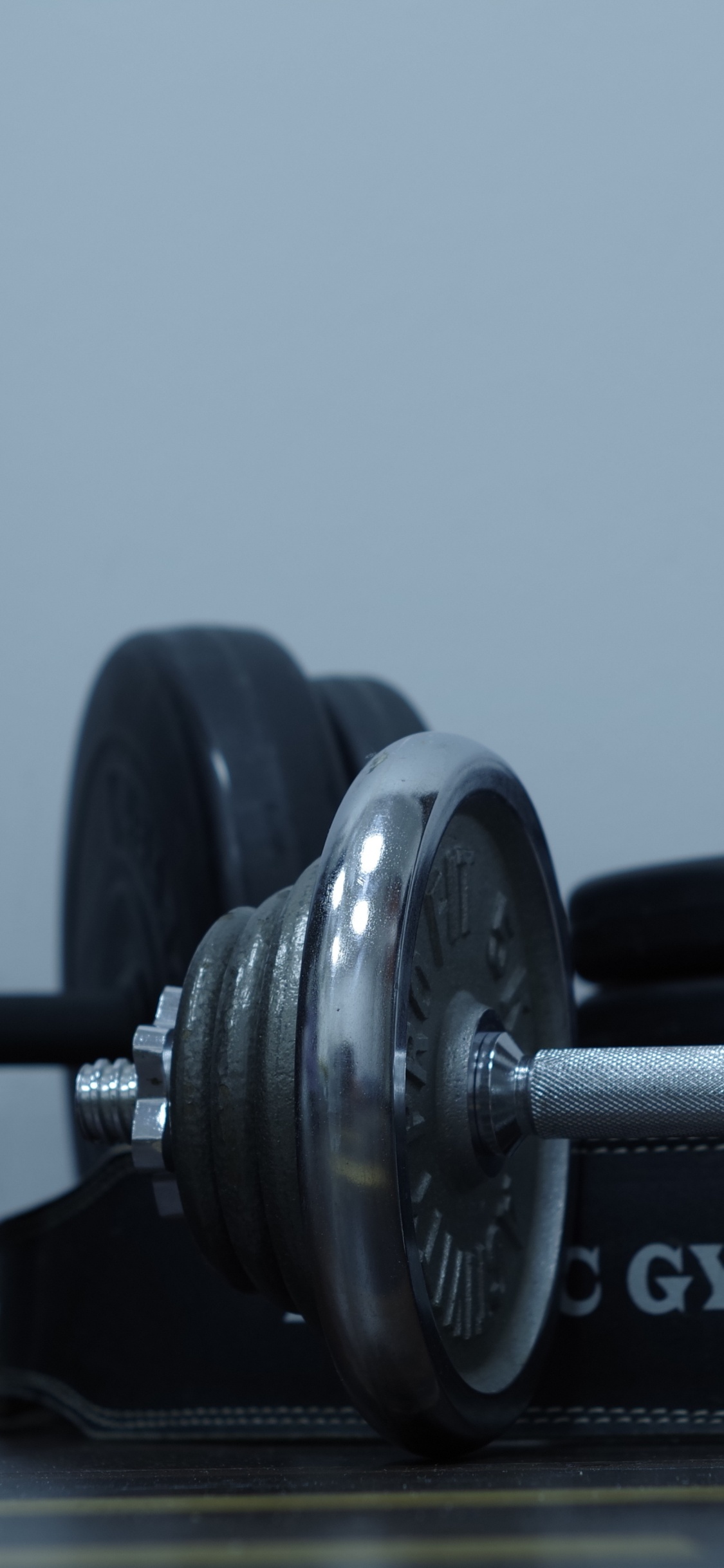 2 Black Dumbbells on Brown Wooden Table. Wallpaper in 1125x2436 Resolution