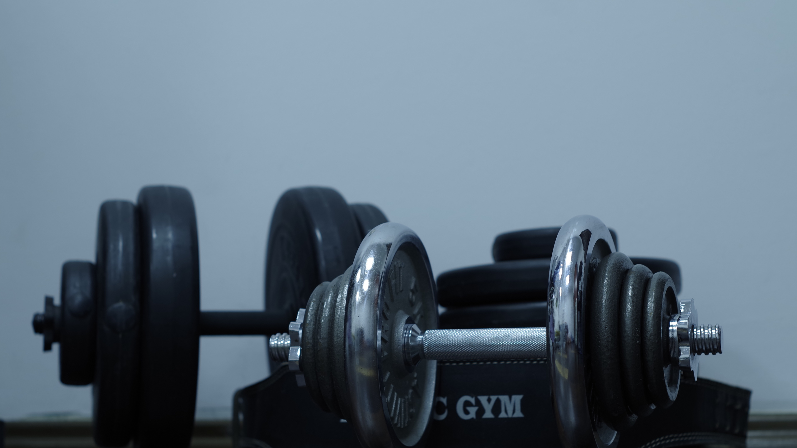 2 Black Dumbbells on Brown Wooden Table. Wallpaper in 2560x1440 Resolution