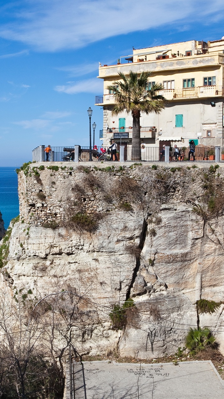 Weißes Betongebäude Auf Braunem Felsigem Berg Unter Blauem Himmel Tagsüber. Wallpaper in 720x1280 Resolution